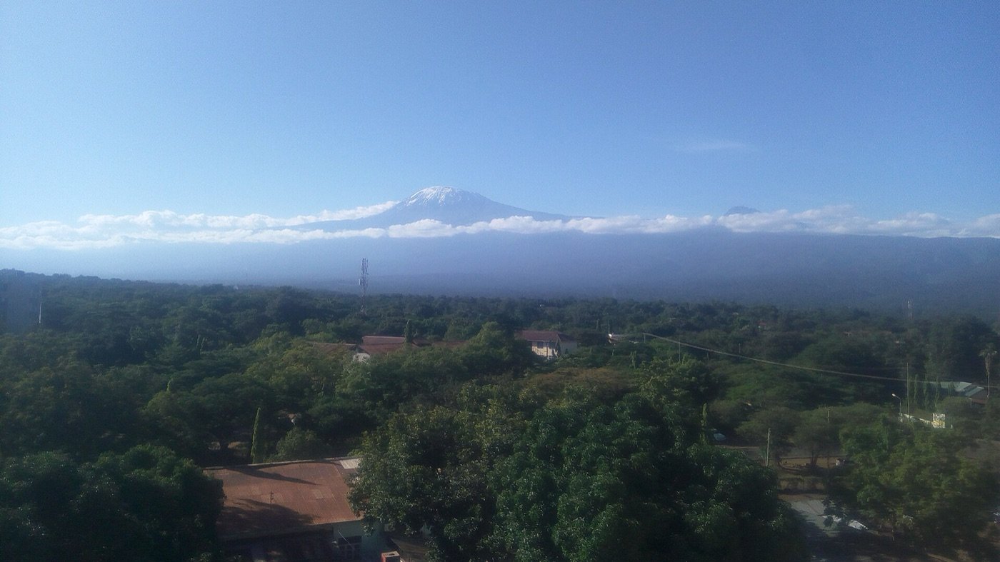 Snow-capped Mount Kilimanjaro rising above the green town of Moshi
